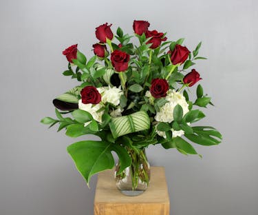 This elegant floral arrangement features a dozen striking red Explorer roses artfully arranged in a sleek clear glass vase.