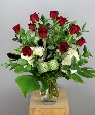 This elegant floral arrangement features a dozen striking red Explorer roses artfully arranged in a sleek clear glass vase.