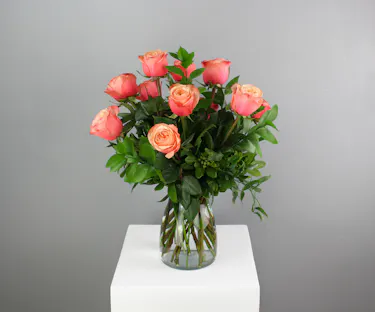 A timeless display of grace and beauty, this arrangement features a dozen exquisite peach Kahala roses showcased in a classic clear glass vase.