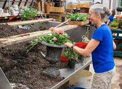 A smiling Radebaugh employee pots a plant in our designers' workroom